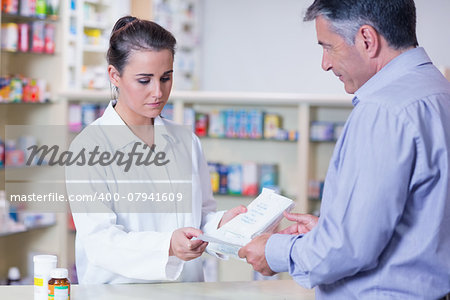 Customer handing a prescription to a trainee in the pharmacy