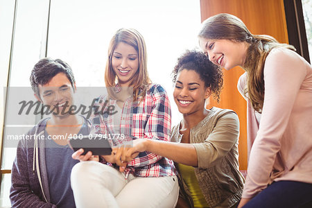 Happy student holding smartphone showing screen at the university