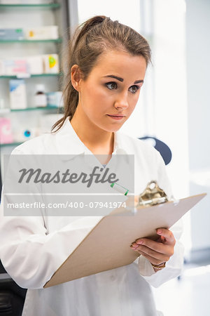 Junior pharmacist writing on clipboard at the hospital pharmacy