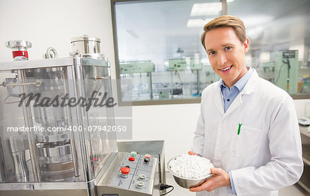 Happy pharmacist showing bowl of pills at the hospital pharmacy