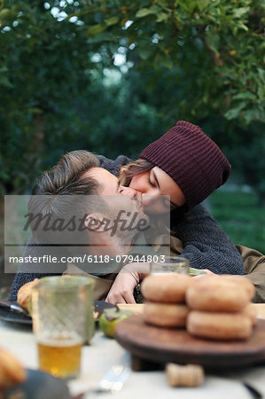 An apple orchard in Utah. A couple kissing, food and drink on a table.