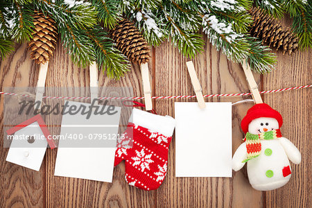 Snow fir tree, photo frames and christmas decor on rope over rustic wooden board with copy space