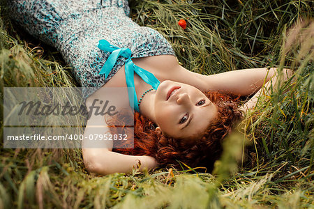 Young woman lying on poppies and smiling looking at camera