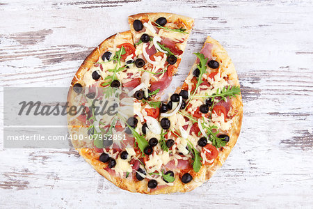 Delicious colorful round pizza on white wooden background, top view. Rustic style traditional delicious pizza eating.