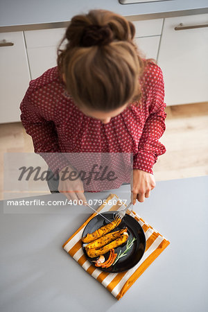 Young housewife eating baked pumpkin