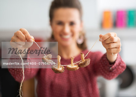 Closeup on young housewife showing mushrooms on string