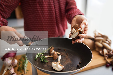 Closeup on young housewife cooking mushrooms