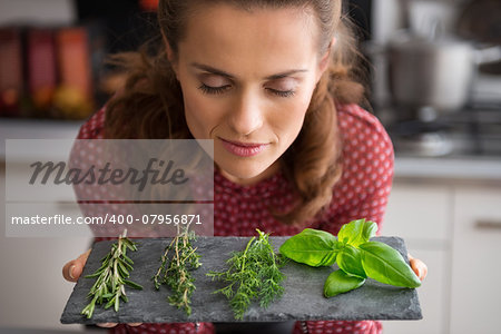 Portrait of young housewife enjoying fresh spices herbs