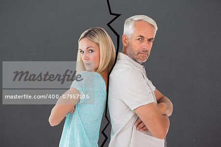 Unhappy couple not speaking to each other  against grey