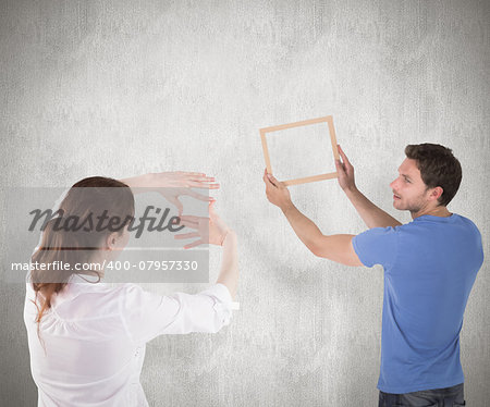 Couple deciding to hang picture against weathered surface