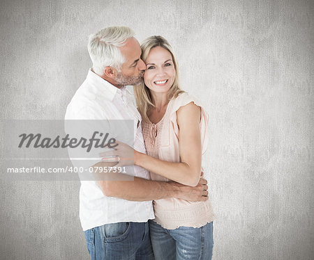 Affectionate man kissing his wife on the cheek against weathered surface
