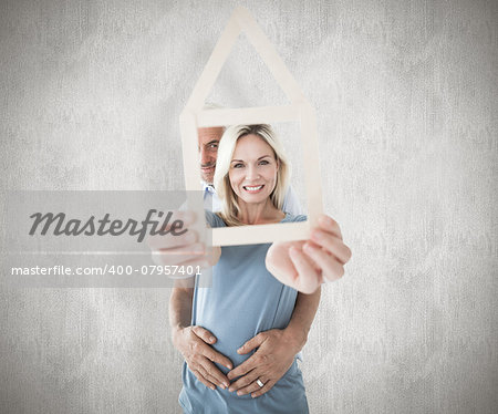 Happy couple holding house outline  against weathered surface