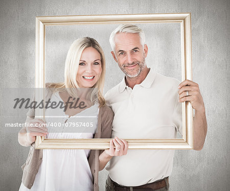 Happy couple holding a picture frame against weathered surface