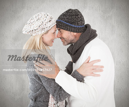 Happy couple in winter fashion embracing against weathered surface
