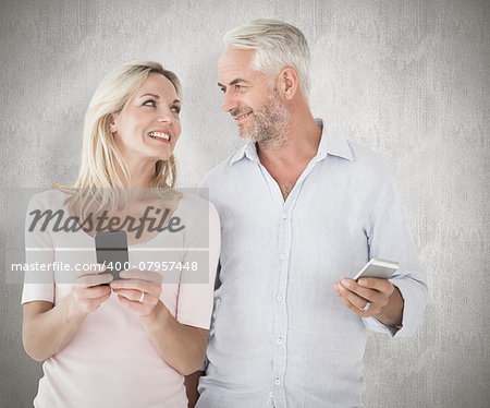Happy couple texting on their smartphones against weathered surface