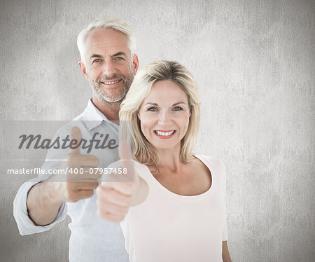 Smiling couple showing thumbs up together against weathered surface