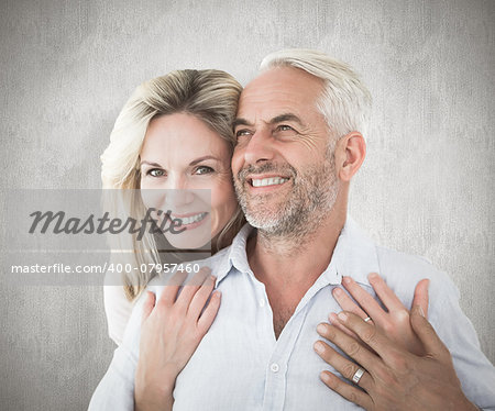 Smiling couple embracing with woman looking at camera against weathered surface