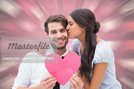 Pretty brunette giving boyfriend a kiss and her heart against valentines heart pattern
