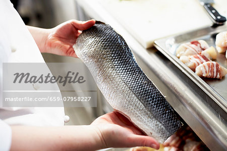 A chef holding a raw fish fillet