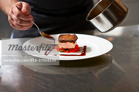 Salmon fillet and gravy being arranged on a plate