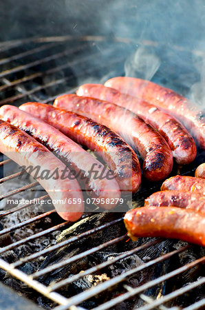 Chipolata sausages on a smoking barbecue Chipolata sausages on a smoking barbecue