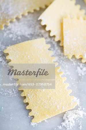 Fresh egg pasta shapes on a floured marble surface Fresh egg pasta shapes on a floured marble surface