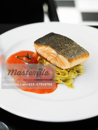 Fried salmon steak on a bed of green tagliatelle with tomato sauce Fried salmon steak on a bed of green tagliatelle with tomato sauce