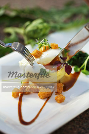 A poached egg served an artichoke heart with Madeira sauce and croutons