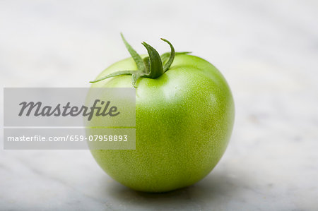 A green tomato on a marble platter