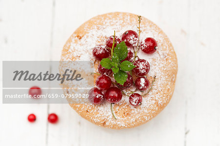 A mini cake with redcurrants and icing sugar