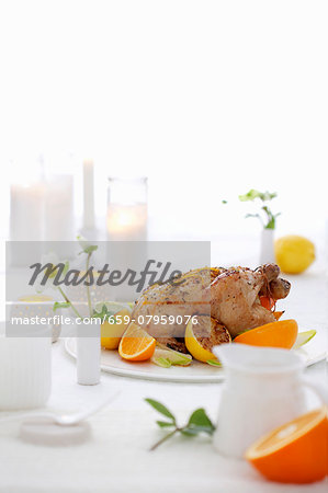 Roast chicken with lemons and oranges on a laid table