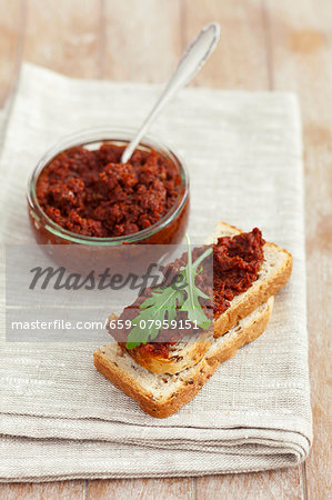 Dried tomato pesto on slice of white bread and in a jar