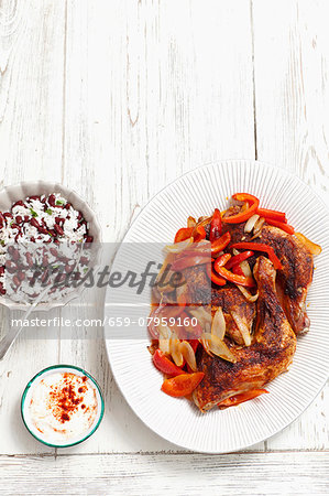 Roast chicken legs with peppers and onions served with a side of rice Roast chicken legs with peppers and onions served with a side of rice
