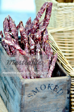 Mini salamis in a wooden crate at a market