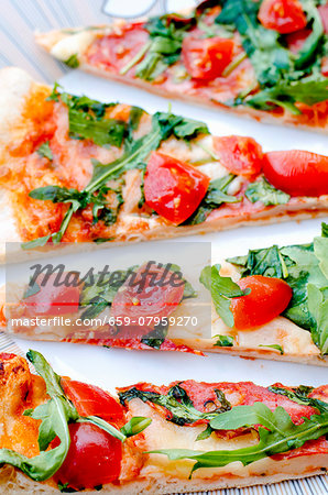 Slices of pizza topped with fresh rocket and cherry tomatoes