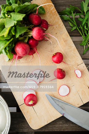 Radishes, partially sliced, on a chopping board