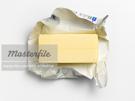 An unwrapped pat of butter on its wrapper