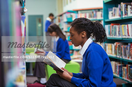 High School students sitting and reading book in library
