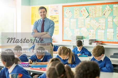 Portrait of smiling teacher and elementary school children in classroom