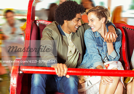 Cheerful couple on carousel in amusement park
