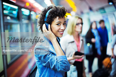 Smiling woman listening to headphones in subway Smiling woman listening to headphones in subway