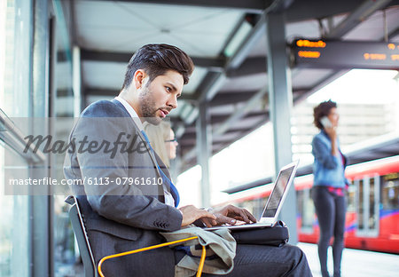 Businessman using laptop at train station Businessman using laptop at train station