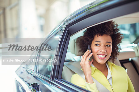 Businesswoman talking on cell phone in back seat of car