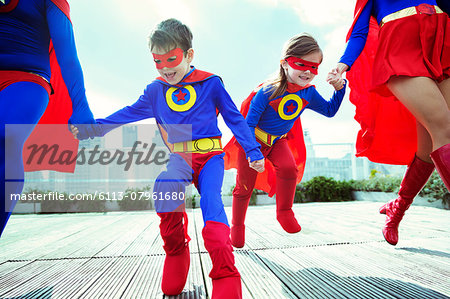 Family of superheroes running on city rooftop