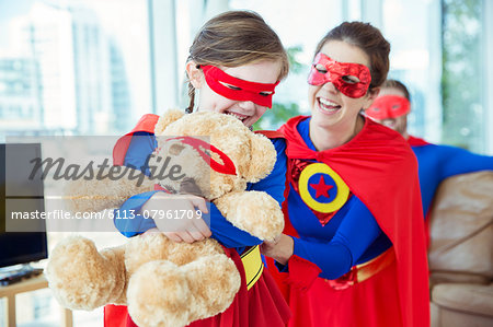 Superhero mother and daughter playing with teddy bear