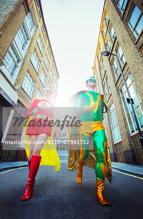 Low angle view of superhero couple running on city street