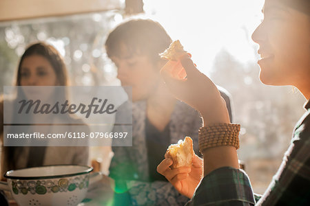 Three people sitting at a table, smiling, eating and chatting.