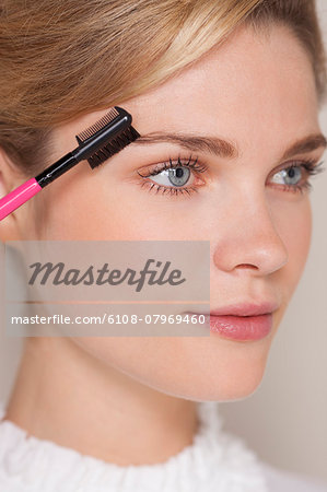 Beautiful woman brushing her eyebrow