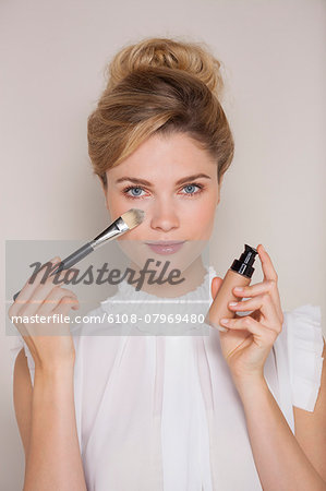 Beautiful woman applying make-up with blusher