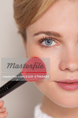 Portrait of a woman using make-up brush on her face